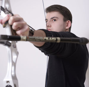 Man aiming with bow and arrow against white background