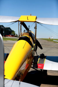 Close-up of yellow plane against blue sky 