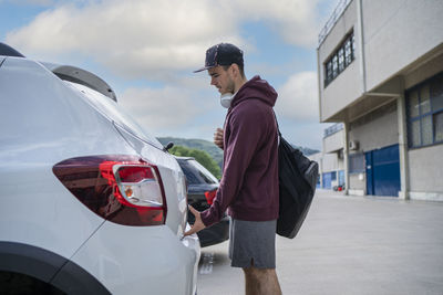 Man standing by car on city street