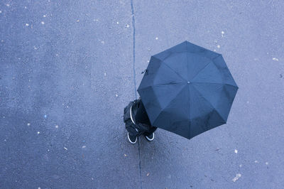 Directly above shot of person standing with umbrella on road during monsoon