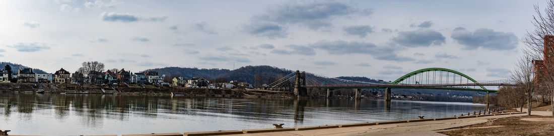 Bridge over river in city against sky