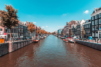 Canal amidst buildings in city against sky