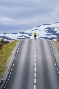 Rear view of man on snow covered road against sky