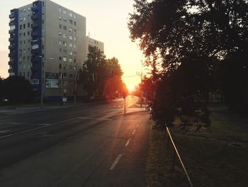 Road passing through city at sunset