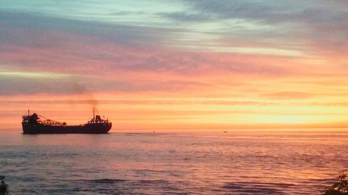 Boats sailing in sea at sunset