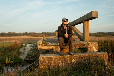 A man sitting on an old bridge, evening view