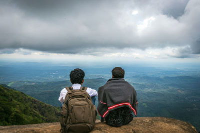 Rear view of people looking at mountains against sky