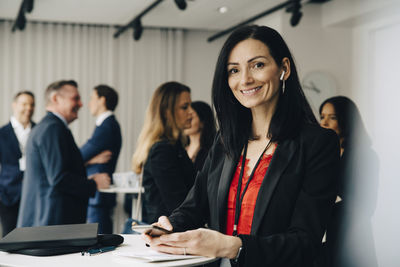 Portrait of smiling entrepreneur with phone at office seminar