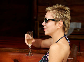 Side view of woman holding champagne while sitting at restaurant