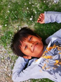 High angle view of smiling boy lying on land