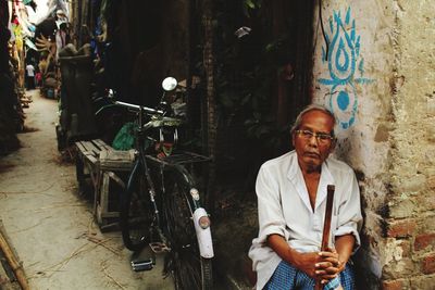 Mature man sitting against building in town