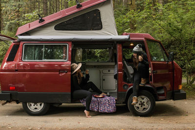 Female friends talking while sitting in motor home at forest