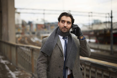 Businessman talking on phone at train station