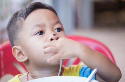 Close-up of cute boy with nose injury eating food while sitting at home