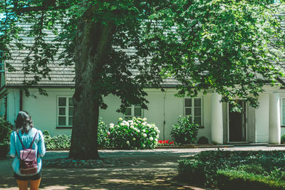 Woman standing by tree against building