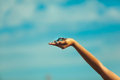 Close-up of woman hand holding umbrella against blue sky