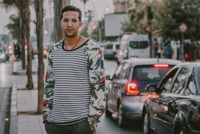 Portrait of young man standing on street in city