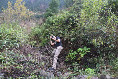 Side view of person photographing through smart phone in forest