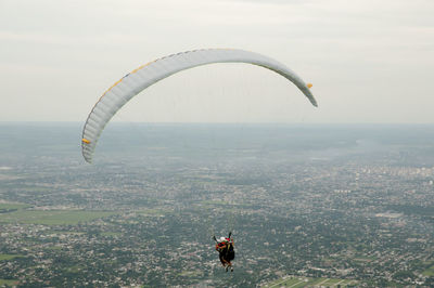 High angle view of people paragliding over landscape against sky