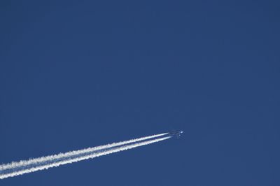 Low angle view of airplane flying against clear blue sky