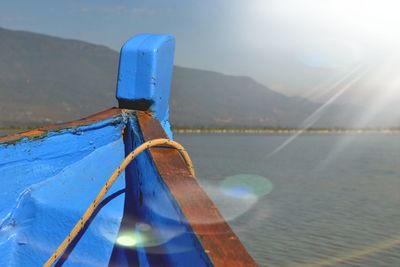 Close-up of sailboat in sea against mountains