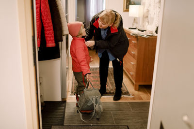 Senior woman wearing warm clothes to grandson at home