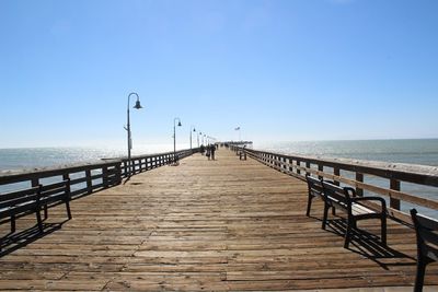 Pier over sea against clear blue sky