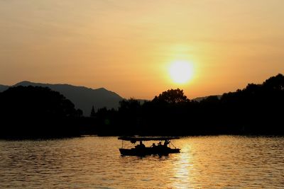 Silhouette of people in river at sunset