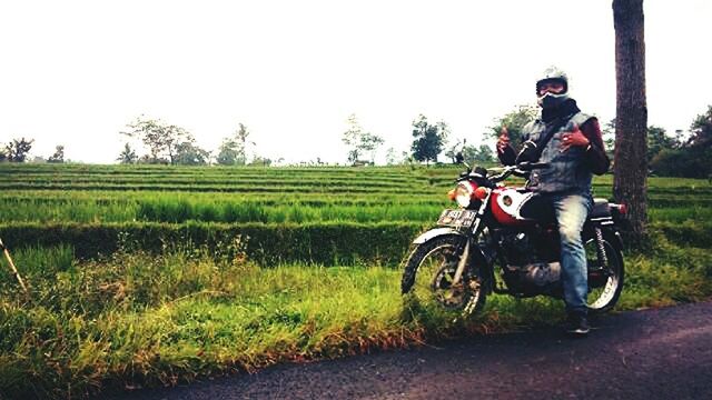 transportation, land vehicle, bicycle, grass, mode of transport, lifestyles, field, leisure activity, clear sky, men, full length, riding, casual clothing, agriculture, copy space, rural scene, landscape, grassy