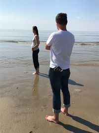 Rear view of men standing on beach