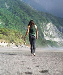 Rear view of woman walking on sand at beach