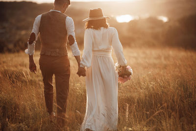 Rear view of couple on field during sunset
