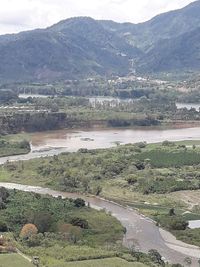 High angle view of river by mountains against sky