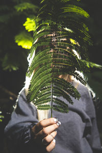 Woman covering face with plants