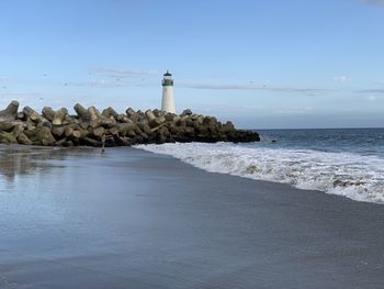 Lighthouse by sea against sky