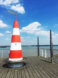 Red lighthouse by sea against sky