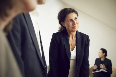 Confident businesswoman looking away while standing with lawyers at office during meeting