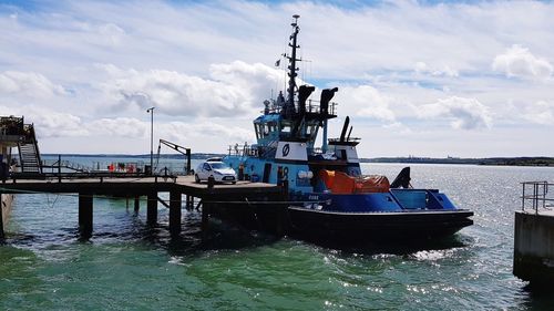 Ship moored at harbor against sky