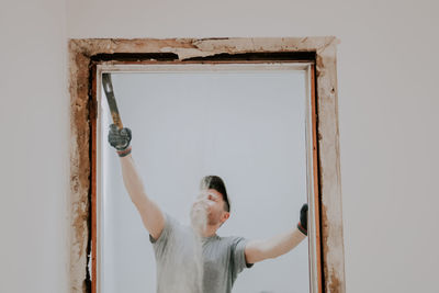 A man working with a crowbar in a doorway.