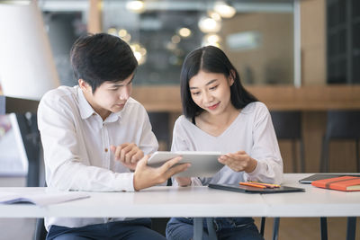 Young couple looking at camera while sitting on table