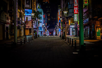 Illuminated street amidst buildings in ikebukuro city at night