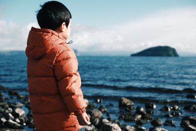 Close-up of boy standing at beach against sky