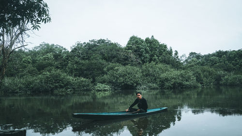 Man on boat in lake against sky