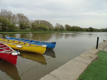 Boats moored on lake against sky