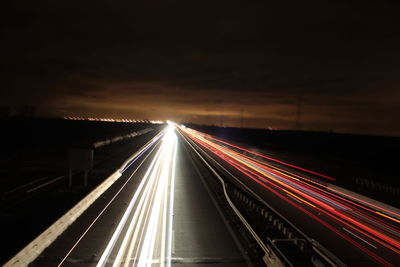 Light trails on road against sky at night
