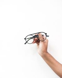 Close-up of hand holding eyeglasses against white background