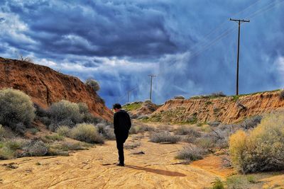 Man standing by rock formation against sky