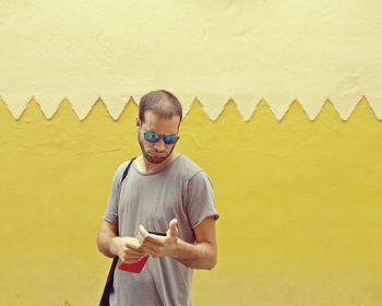 Portrait of boy standing against yellow wall