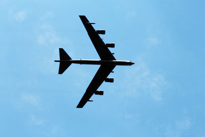 Low angle view of military airplane flying against sky on sunny day