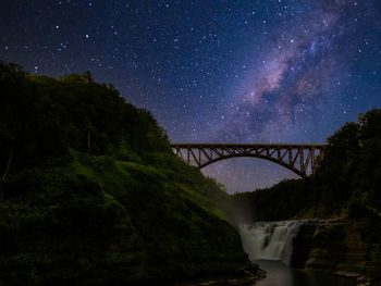 Bridge over river against sky at night